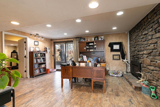 office featuring crown molding, hardwood / wood-style floors, a textured ceiling, and a fireplace