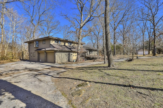 view of side of home featuring a garage and a lawn