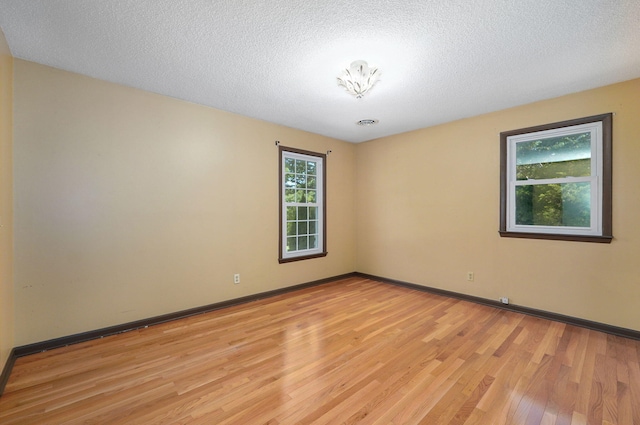 empty room featuring a textured ceiling and light hardwood / wood-style floors