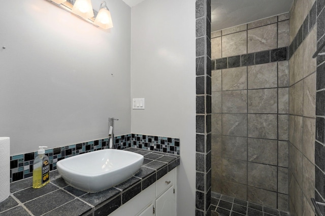 bathroom with vanity, decorative backsplash, and a tile shower