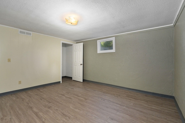 unfurnished room with crown molding, hardwood / wood-style floors, and a textured ceiling