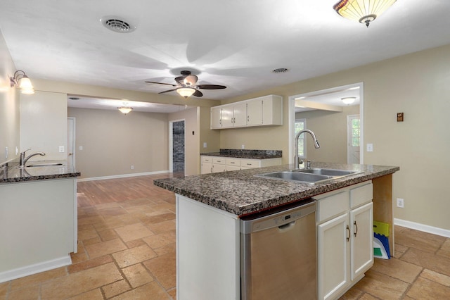 kitchen featuring an island with sink, sink, stainless steel dishwasher, and white cabinets