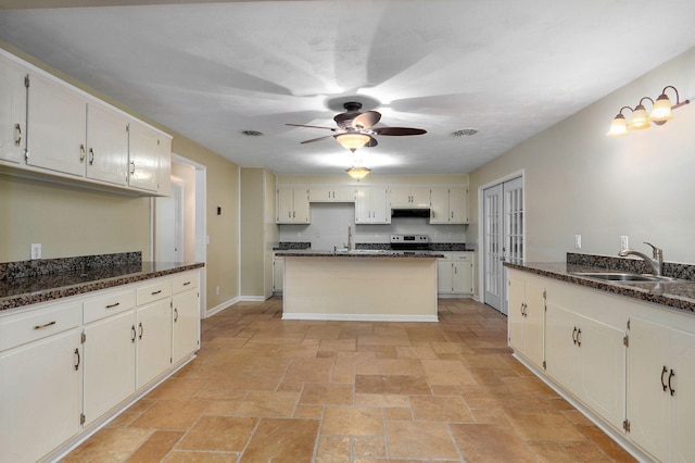 kitchen featuring ceiling fan, dark stone counters, sink, and stainless steel range with electric cooktop