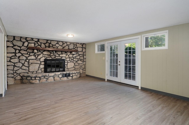 unfurnished living room featuring french doors, a fireplace, and light wood-type flooring