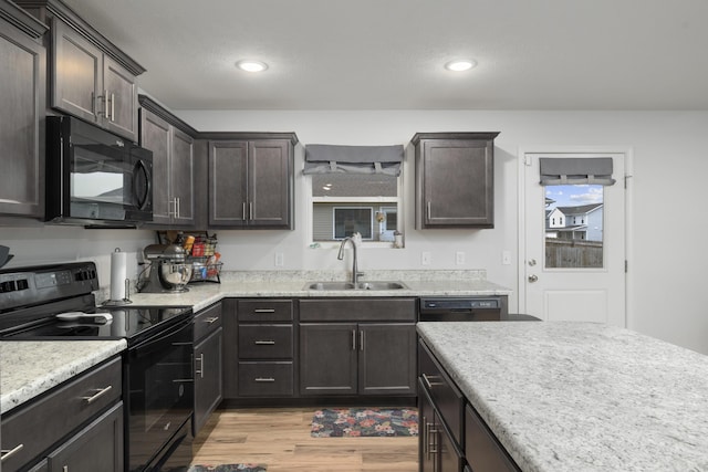 kitchen featuring dark brown cabinets, sink, light hardwood / wood-style flooring, and black appliances