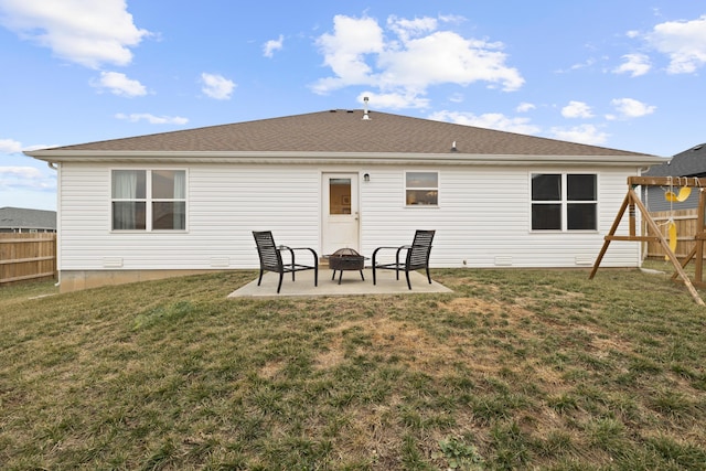 rear view of house with a playground, a patio, a yard, and an outdoor fire pit