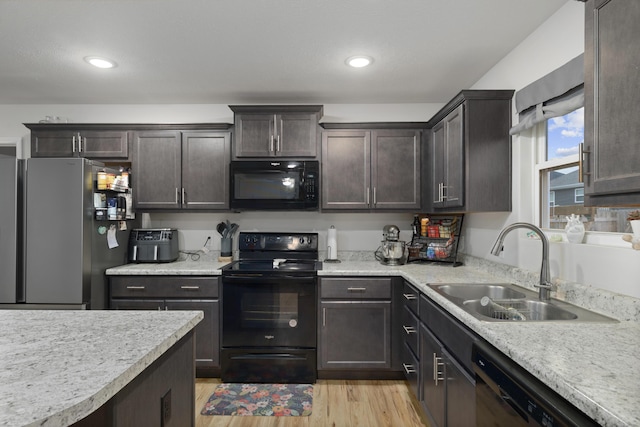 kitchen featuring dark brown cabinetry, sink, black appliances, and light hardwood / wood-style floors