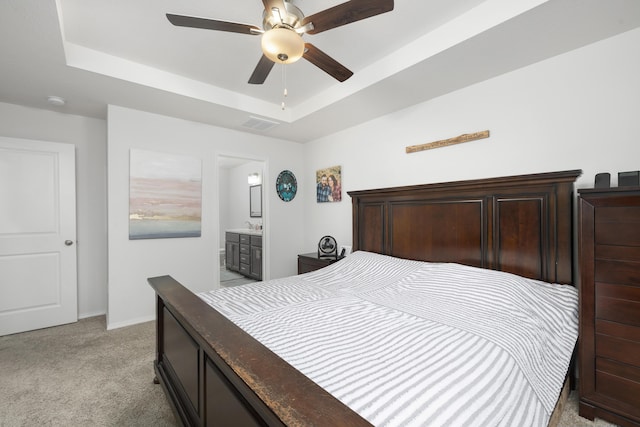 bedroom featuring connected bathroom, sink, ceiling fan, a raised ceiling, and light carpet