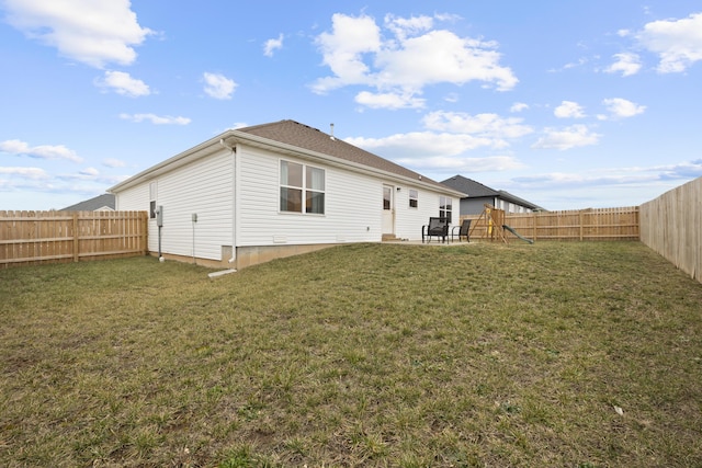 back of house featuring a yard and a playground