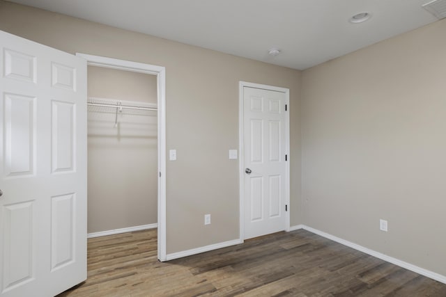 unfurnished bedroom with a spacious closet, hardwood / wood-style floors, and a closet