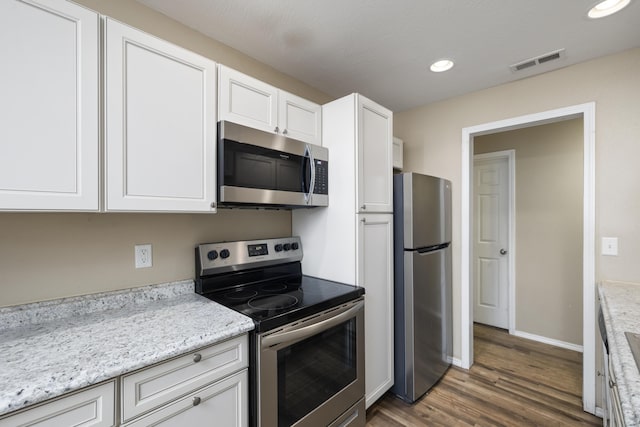 kitchen with white cabinetry, light stone countertops, stainless steel appliances, and dark hardwood / wood-style floors