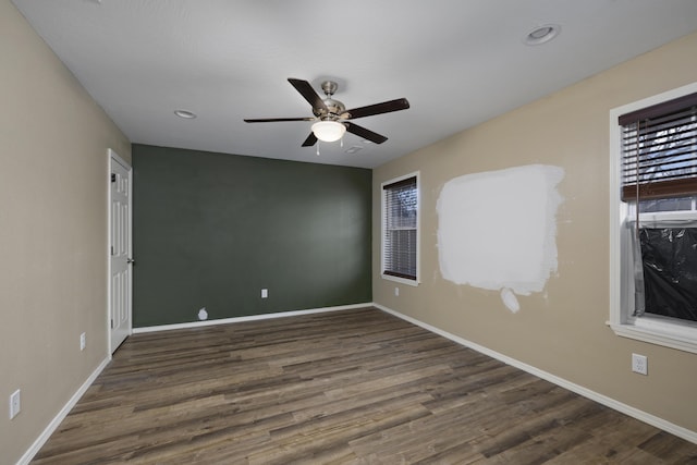 spare room with dark wood-type flooring, ceiling fan, and a healthy amount of sunlight