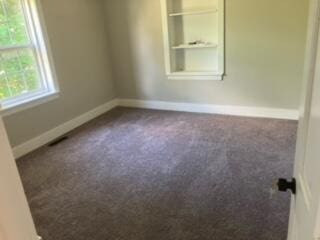 carpeted empty room featuring built in shelves