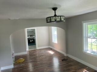 unfurnished dining area with an inviting chandelier and dark hardwood / wood-style flooring