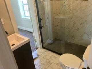 bathroom with vanity, toilet, and tiled shower