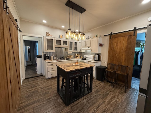 kitchen with pendant lighting, white cabinets, a barn door, and electric range