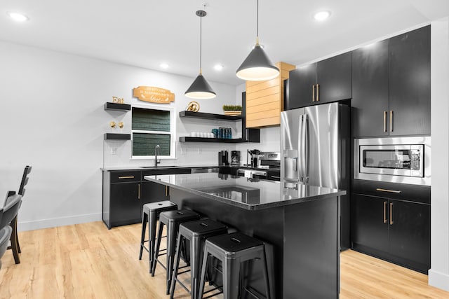 kitchen featuring a kitchen island, appliances with stainless steel finishes, pendant lighting, sink, and a kitchen bar