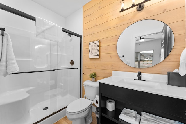 bathroom featuring vanity, a shower with shower door, toilet, and wood walls