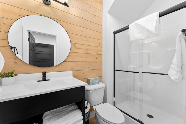 bathroom featuring toilet, vanity, wooden walls, and a shower with shower door