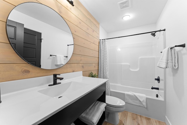 full bathroom featuring toilet, wood walls, wood-type flooring, vanity, and shower / bath combo