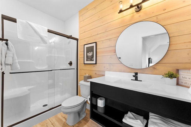 bathroom with hardwood / wood-style floors, wooden walls, vanity, toilet, and walk in shower