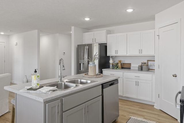 kitchen with sink, light hardwood / wood-style flooring, stainless steel appliances, white cabinets, and a center island with sink