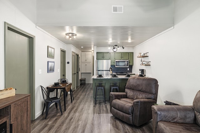 living room with track lighting, ornamental molding, sink, and hardwood / wood-style floors