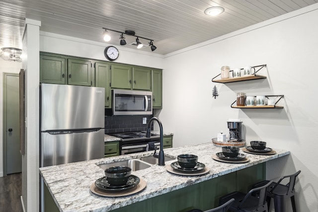 kitchen with a breakfast bar, appliances with stainless steel finishes, kitchen peninsula, green cabinets, and light stone countertops