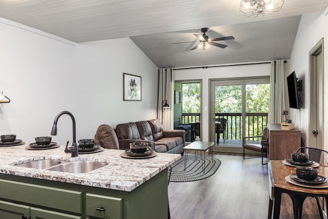 kitchen with lofted ceiling, sink, green cabinets, dark hardwood / wood-style floors, and light stone countertops