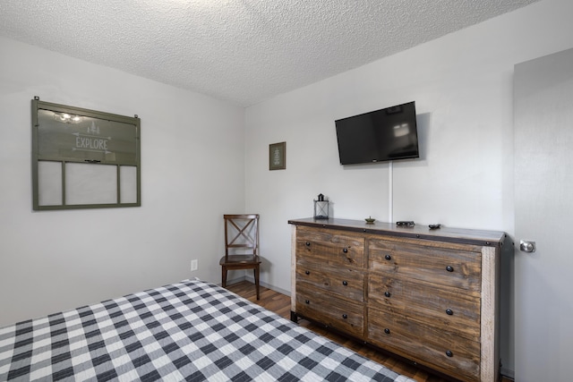 bedroom with dark hardwood / wood-style floors and a textured ceiling