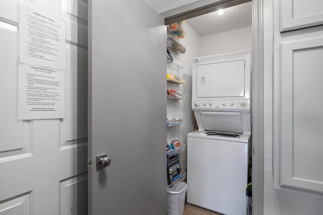 clothes washing area with stacked washer and dryer and a textured ceiling