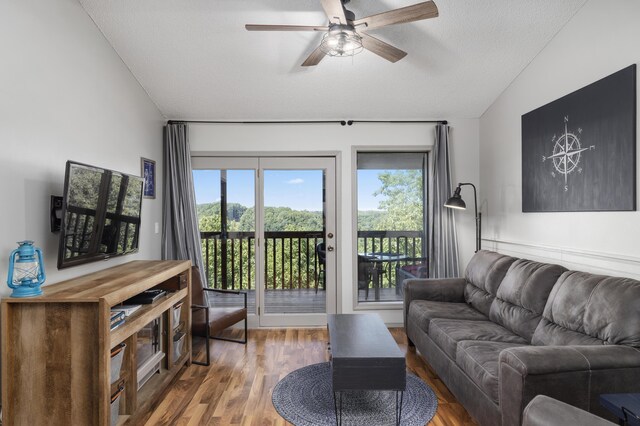 living room with hardwood / wood-style flooring, ceiling fan, lofted ceiling, and a textured ceiling