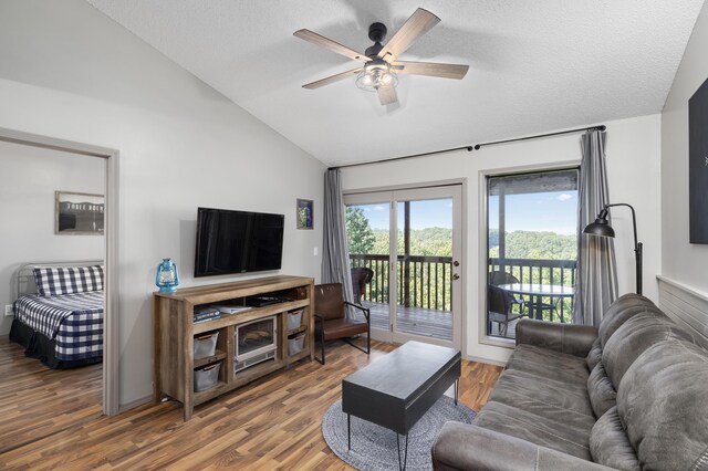 living room with hardwood / wood-style flooring, ceiling fan, vaulted ceiling, and a textured ceiling