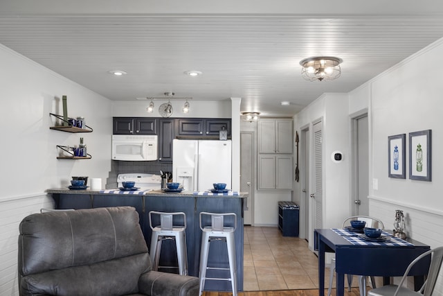 kitchen with gray cabinetry, white appliances, a kitchen breakfast bar, and kitchen peninsula