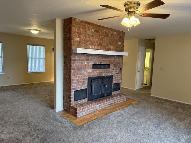 unfurnished living room featuring ceiling fan, a brick fireplace, a textured ceiling, and dark carpet