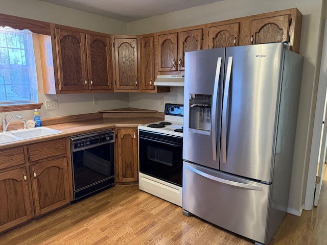 kitchen with sink, stainless steel fridge, electric range oven, black dishwasher, and light wood-type flooring