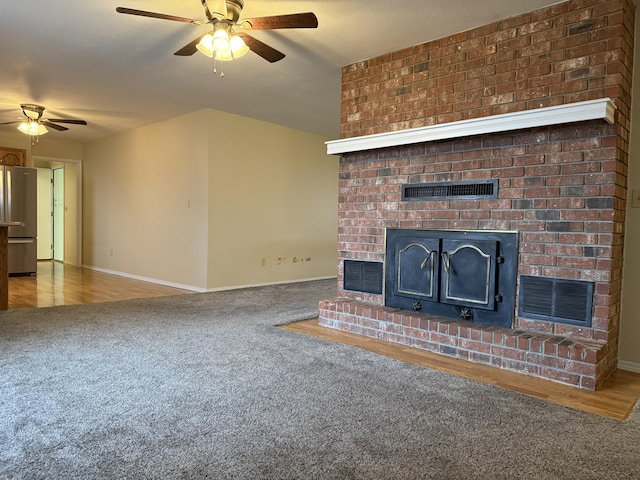 unfurnished living room featuring ceiling fan, carpet flooring, and a fireplace