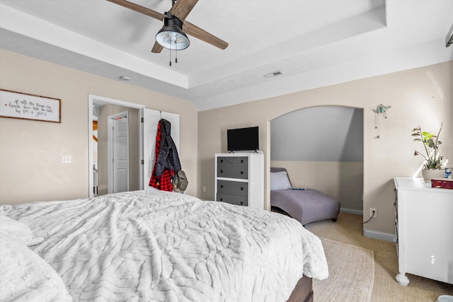 carpeted bedroom featuring ceiling fan and a tray ceiling