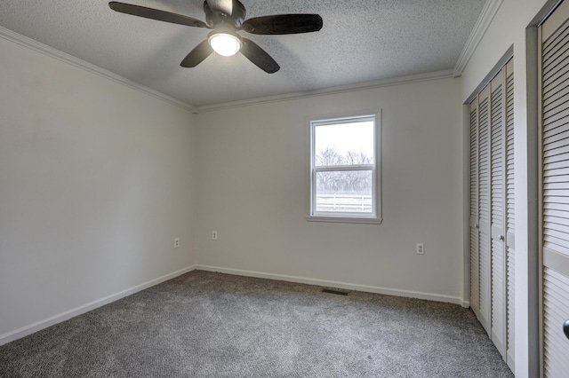 unfurnished bedroom with crown molding, carpet, ceiling fan, and a textured ceiling