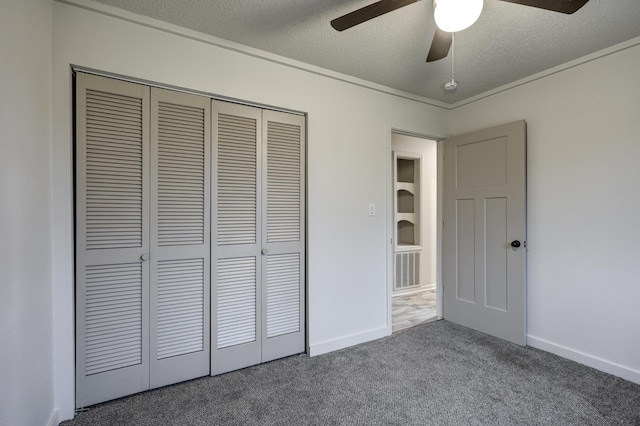 unfurnished bedroom with a textured ceiling, ornamental molding, a closet, ceiling fan, and carpet