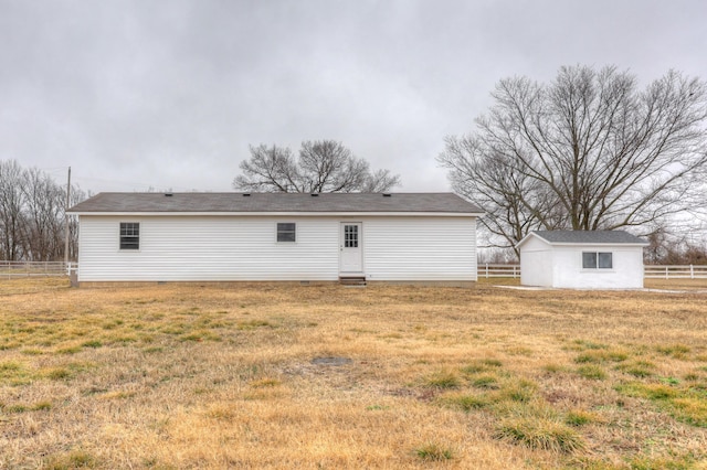 rear view of property featuring a shed and a lawn