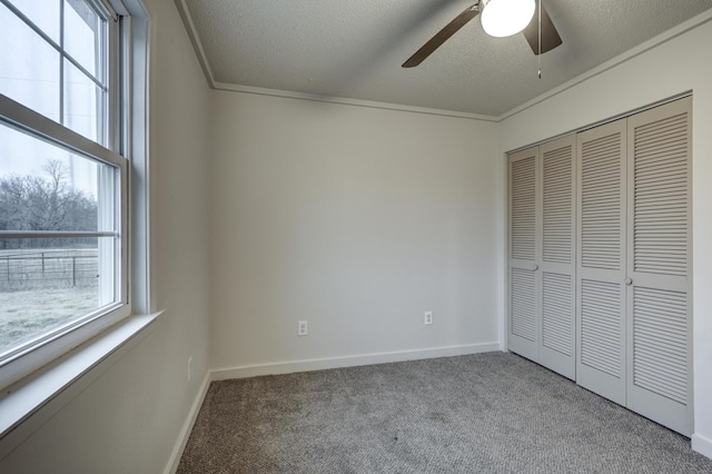 unfurnished bedroom featuring a closet, carpet flooring, multiple windows, and a textured ceiling