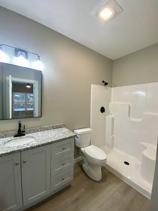 bathroom with vanity, hardwood / wood-style floors, a shower, and toilet