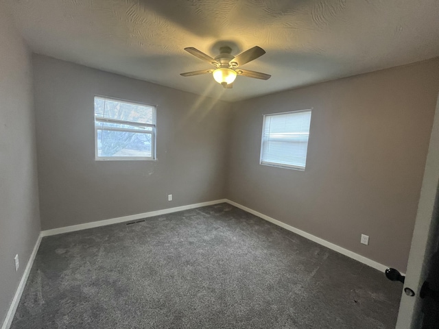 unfurnished room with ceiling fan, a textured ceiling, and dark colored carpet