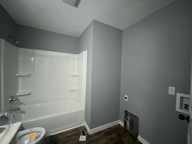 bathroom with washtub / shower combination, toilet, and hardwood / wood-style floors