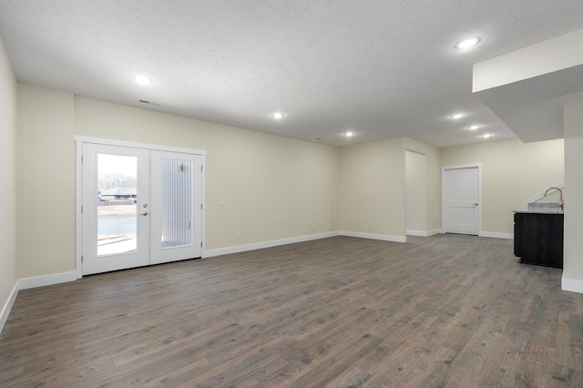 unfurnished living room with a textured ceiling, dark hardwood / wood-style flooring, and french doors