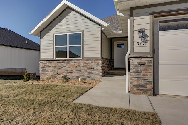 doorway to property with a garage and a yard