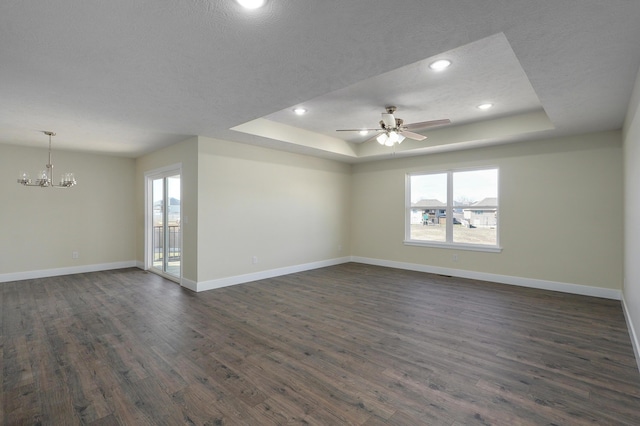 unfurnished room with a raised ceiling, ceiling fan with notable chandelier, a textured ceiling, and dark hardwood / wood-style flooring