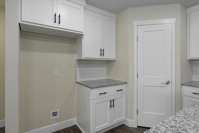 kitchen with light stone counters, dark hardwood / wood-style floors, backsplash, and white cabinets