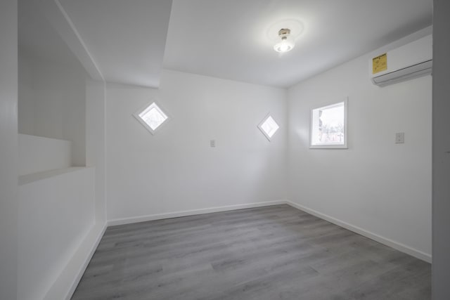 spare room with plenty of natural light, an AC wall unit, and light hardwood / wood-style flooring
